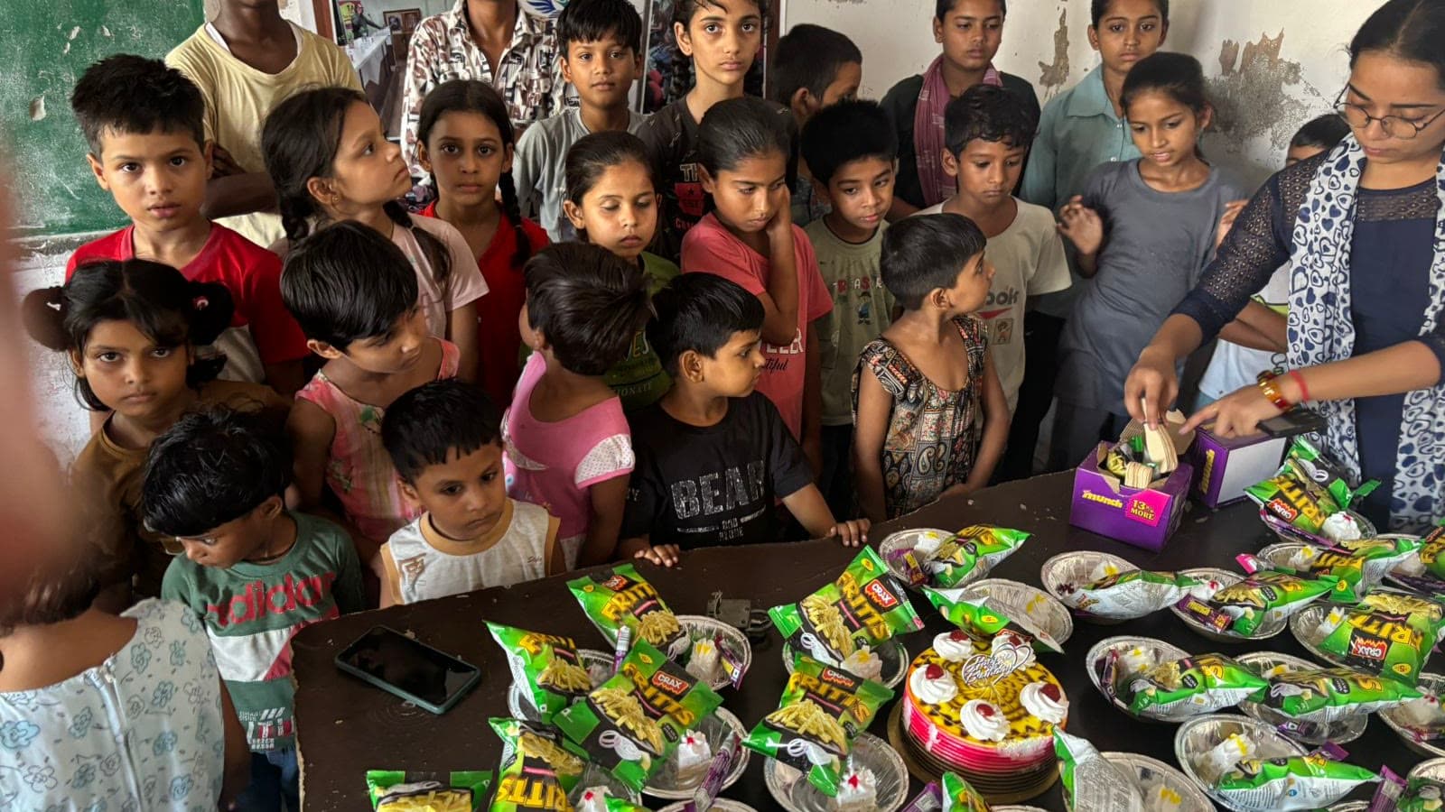Children gathered around a table of food packets at a Dreamwings distribution drive